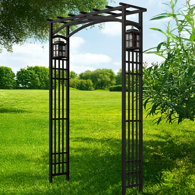 The Garden Entry Arbor standing tall in a lush garden, showcasing its stylish, Mission-style design with steel side panels and lantern holders. This arbor creates a grand and dramatic entrance for any outdoor space